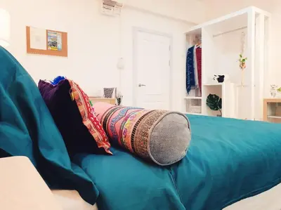 a blue couch with a pillow on top of it at Double Studio, Private Bath & Balcony, Shared Kitchen with Local Family by Pillows & Purrs in Bangkok