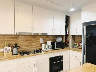 a kitchen with white cabinets and a black refrigerator at Single Beds, Private Bath & Balcony, Shared Kitchen with Local Family by Pillows & Purrs in Bangkok