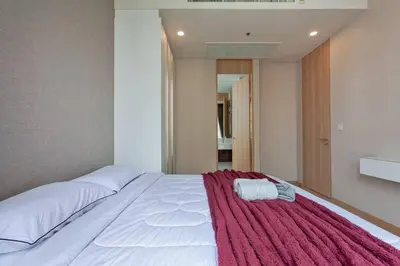 a bedroom with a large white bed with a red blanket at New 2-Bedroom Apartment in Asok in Bangkok