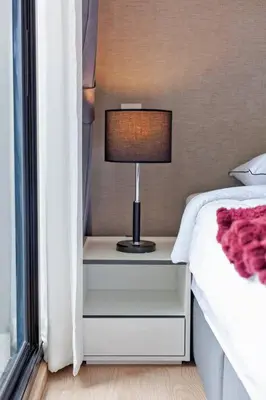 a lamp on a night stand next to a bed at New 2-Bedroom Apartment in Asok in Bangkok