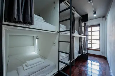 a room with four bunk beds and a mirror at Mascotte Hostel Silom in Bangkok
