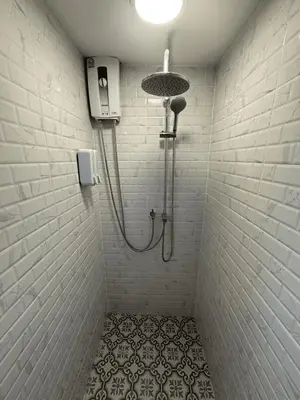 a shower in a bathroom with a tile floor at First Villa Life Hostel in Bangkok