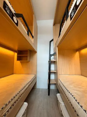 two bunk beds in a room with wooden shelves at First Villa Life Hostel in Bangkok