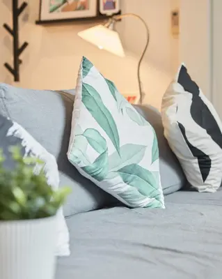 a couch with pillows and a plant on it at Spacious Design Loft with Rooftop in Bangkok