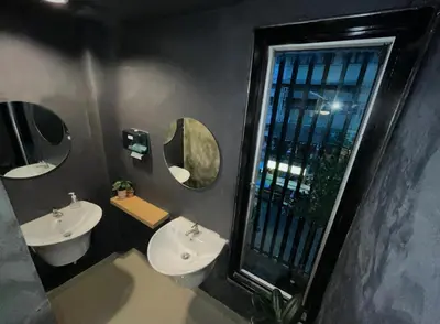 a bathroom with two sinks and mirrors and a window at Bud Brew Beyond Dispensary and Hotel in Bangkok