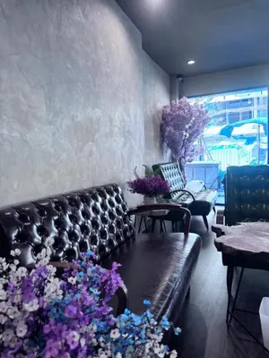 a living room with a leather couch and purple flowers at Bud Brew Beyond Dispensary and Hotel in Bangkok