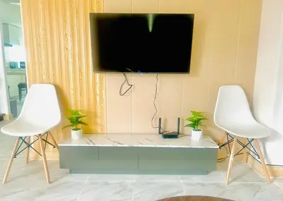 a tv hanging on a wall with two white chairs at 93 House in Ban Bang Toei (1)