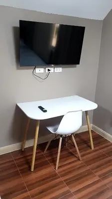 a white table with a chair and a television on a wall at 93 House in Ban Bang Toei (1)