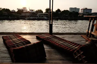 two benches sitting on a dock next to a body of water at Bannai Bangkoknoi บ้านในบางกอกน้อย in Ban Bang Bamru