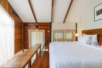 a bedroom with a large bed and a bench at Baanrongmai Canal Front Homestay in Bang Chak