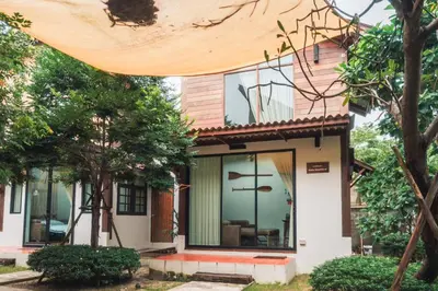 a house with glass doors and trees at Baanrongmai Canal Front Homestay in Bang Chak