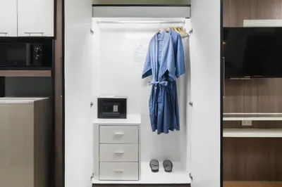 a closet with a blue robe and a tv at Aspira Suites Sukhumvit 20 in Bangkok