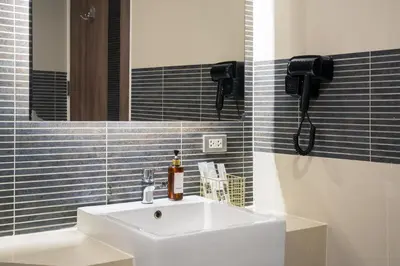 a bathroom with a white sink and a mirror at Aspira Suites Sukhumvit 20 in Bangkok