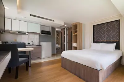 a bedroom with a large bed and a kitchen at Aspira Suites Sukhumvit 20 in Bangkok