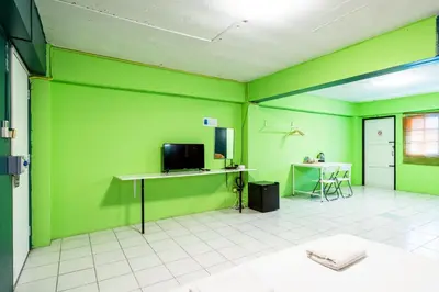a room with green walls and a table with a television at xx GO INN The Grand Palace โกอินน์ MRT สามยอด in Bangkok