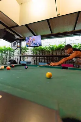 a man playing billiard in a pool table at Revolution Khao San by The Bliss in Bangkok