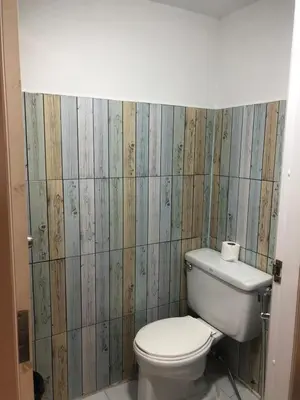 a bathroom with a white toilet and wooden walls at Revolution Khao San by The Bliss in Bangkok