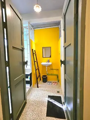 a bathroom with a yellow wall and a sink at Cozy Gallery Studio at Chinatown in Bangkok