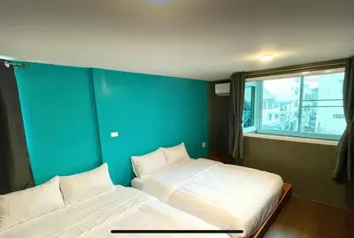 two beds in a room with a blue wall at Purple House King BR Walk to Grand Palace in Bangkok