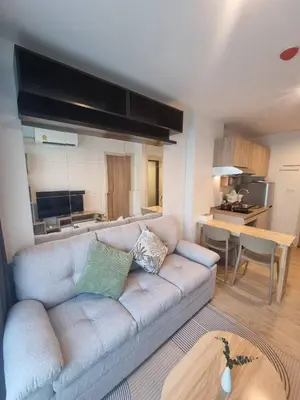 a living room with a couch and a kitchen at คอนโด 1 ห้องนอน ใกล้บีทีเอสอ่อนนุช สายสีเขียว ที่นอนKing Size วิวสระว่ายน้ำ in Amphoe Phra Khanong