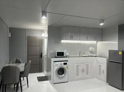 a kitchen with a washing machine and a table with chairs at Impact Donmuang Popular Condo C5 in Bangkok