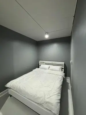 a white bed in a room with a wall at Impact Donmuang Popular Condo C5 in Bangkok