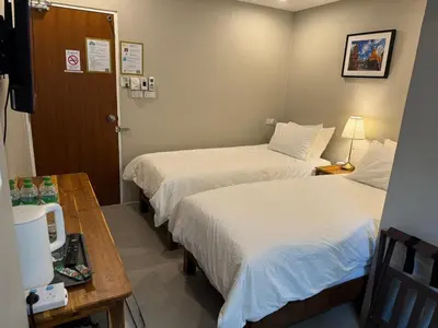 a hotel room with two beds and a desk and a table at Rimm49 Bangkok in Bangkok