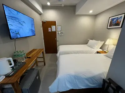 a hotel room with two beds and a tv at Rimm49 Bangkok in Bangkok