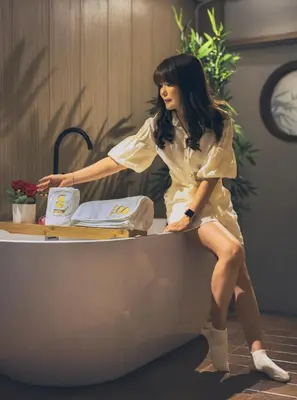 a woman in a dress sitting on a bath tub at SHIN Hotel Chinatown in Khlong San