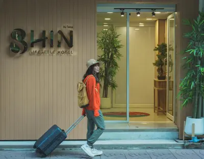 a woman pulling a suitcase in front of a building at SHIN Hotel Chinatown in Khlong San