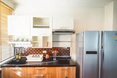 a kitchen with white cabinets and a stainless steel refrigerator at Chezmoi Bangkok Sukhumvit 26 Private Executive Residence 444 in Khlong Toei