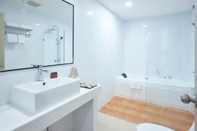 a white bathroom with a sink and a shower at Cozy Donmueang Hotel in Lak Si