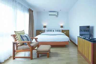 a bedroom with a bed and a chair and a tv at Cozy Donmueang Hotel in Lak Si