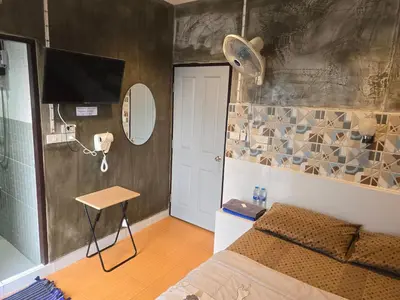 a bedroom with a bed and a table and a mirror at Gail's Hostels in Bangkok