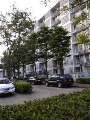 a parking lot with cars parked in front of a building at Savi Rooms Premium 1 Near Bkk Piyavet Hospital in Bangkok