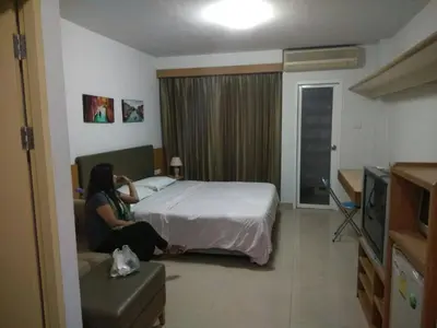 a woman sitting on a bed in a hotel room at Savi Rooms Deluxe 3 Nr Bangkok piyavet Hospital in Bangkok