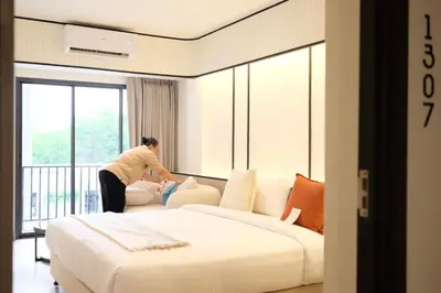 a woman standing next to a bed in a hotel room at Pillow B Hotel in Ban Zong Katiam