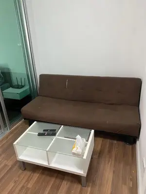 a brown couch in a living room with a coffee table at M Stay in Nonthaburi