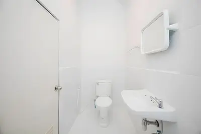 a white bathroom with a toilet and a sink at XX Mitr Inn Yaowarat 2 - มิตร อินน์ เยาวราช in Bangkok