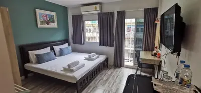 a small room with a bed and two windows at Victory Room in Bangkok