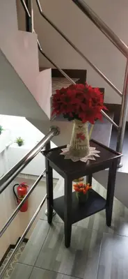 a vase with red flowers on a table under stairs at Victory Room in Bangkok