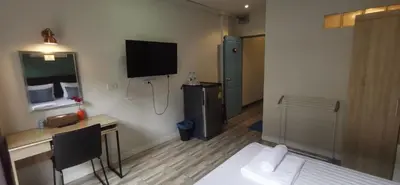 a room with a bed and a desk and a television at Victory Room in Bangkok