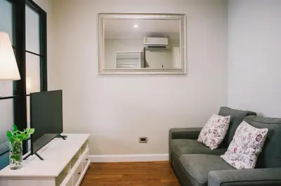 a living room with a couch and a mirror at The Residences at C&C in Bangkok