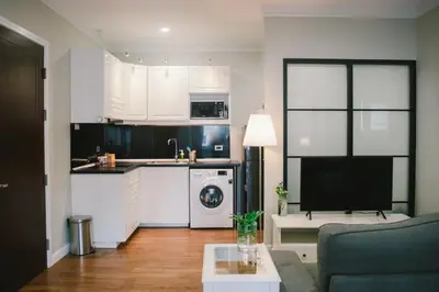 a living room with a couch and a kitchen at The Residences at C&C in Bangkok
