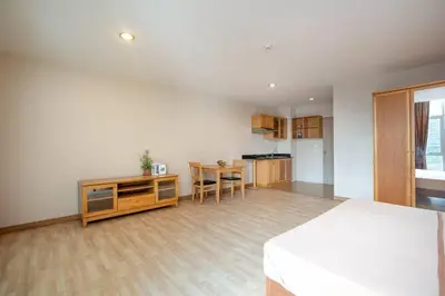 a bedroom with a bed and a table and a kitchen at 181 Ekkamai Studio Apartment in Bangkok
