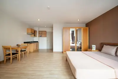a bedroom with a bed and a table and a kitchen at 181 Ekkamai Studio Apartment in Bangkok