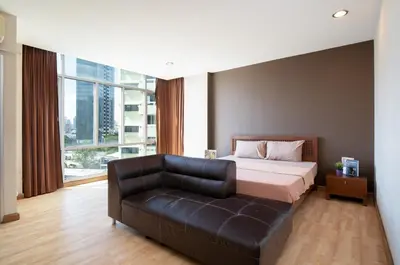 a bedroom with a bed and a leather couch at 181 Ekkamai Studio Apartment in Bangkok