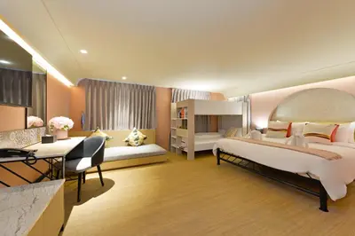 a large bedroom with two beds and a desk at Kastel Bangkok Hotel in Bangkok