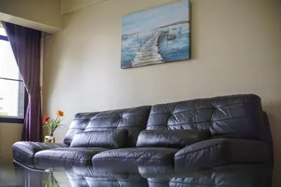 a black leather couch in a living room with a painting at Petch Tower Ekkamai in Bangkok