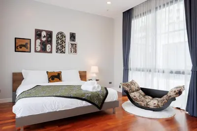 a bedroom with a bed and a chair in front of a window at \u66fc\u8c37\u5e02\u4e2d\u5fc3\u4e03\u5367\u5ba4\u72ec\u680b\u8c6a\u534e\u6cf3\u6c60\u522b\u5885 in Bangkok